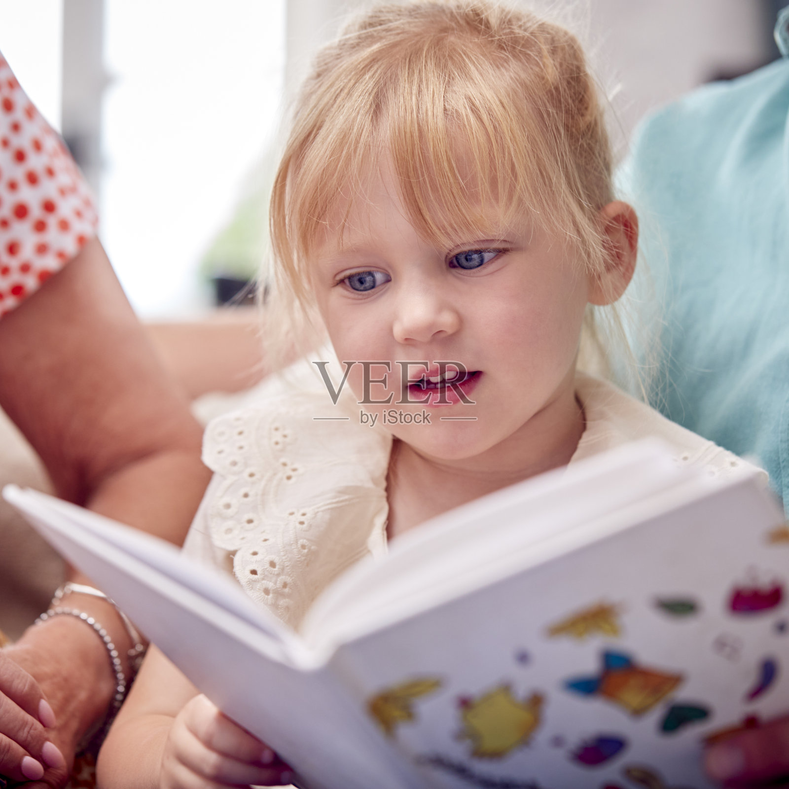 爷爷奶奶和孙女一起坐在沙发上看书照片摄影图片