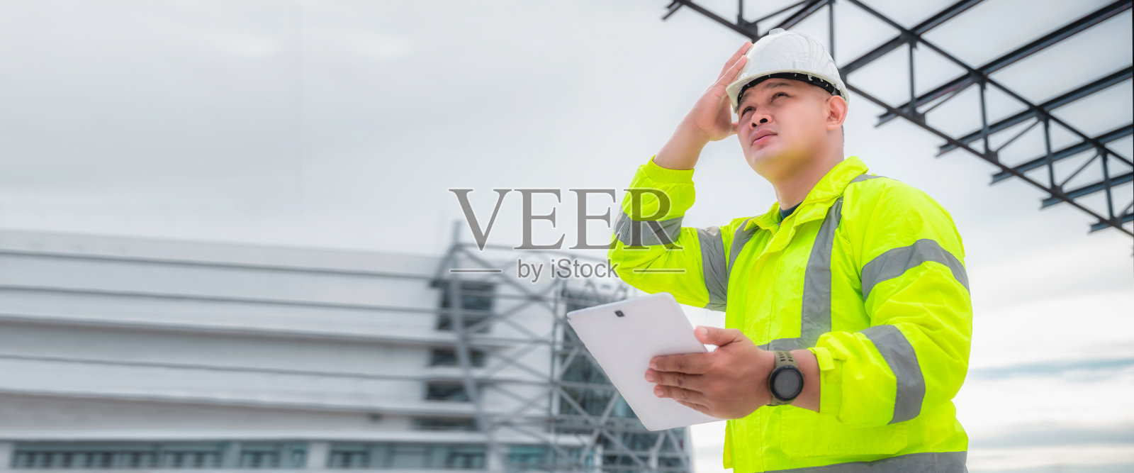 横幅概念:土木工程师检查建筑工地的结构和平面图。土木工程师检查实际施工现场。土木工程师手持牌匾检查建筑。照片摄影图片