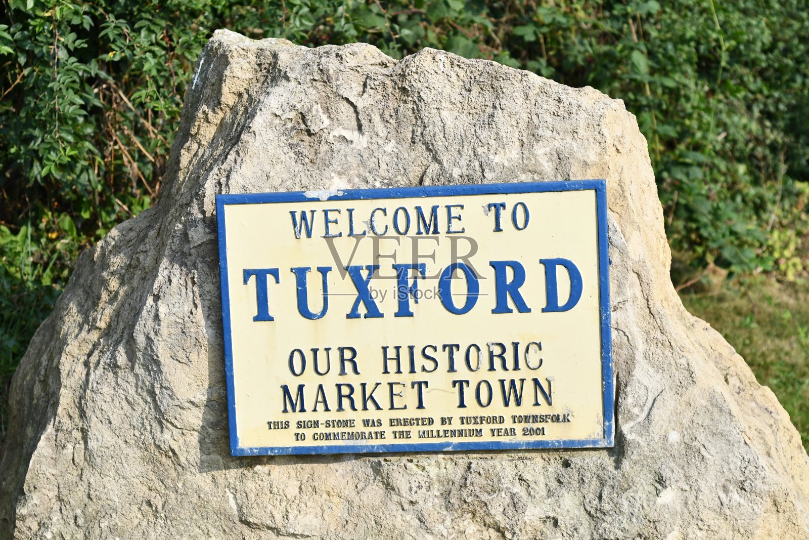 一个突出的村庄标志坐落在一块叫做塔克斯福德的大石头上，历史悠久的集镇，有一个树篱照片摄影图片