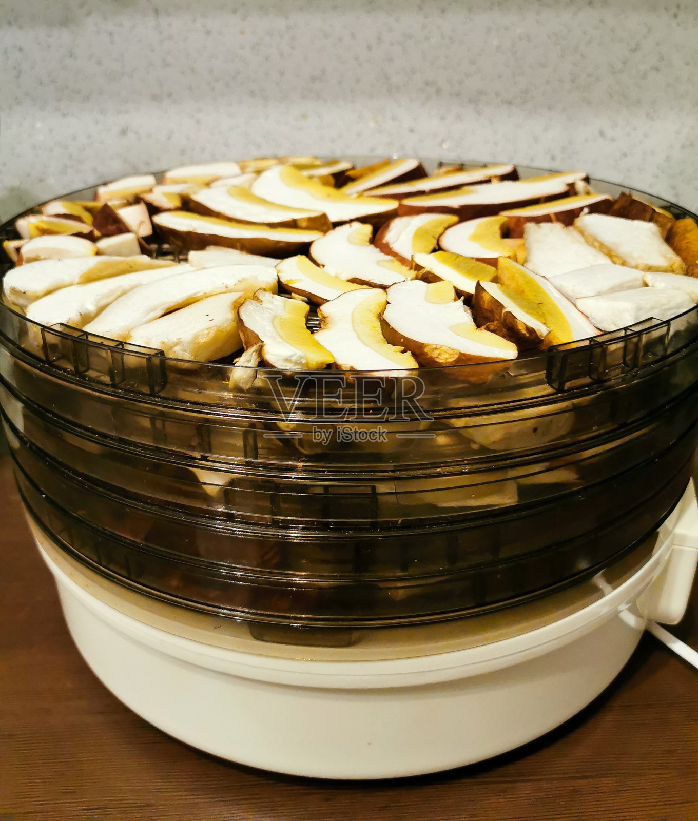 切碎的牛肝菌和牛肝菌的帽和腿放在一个圆形的多层干燥器中，准备晾干。照片摄影图片