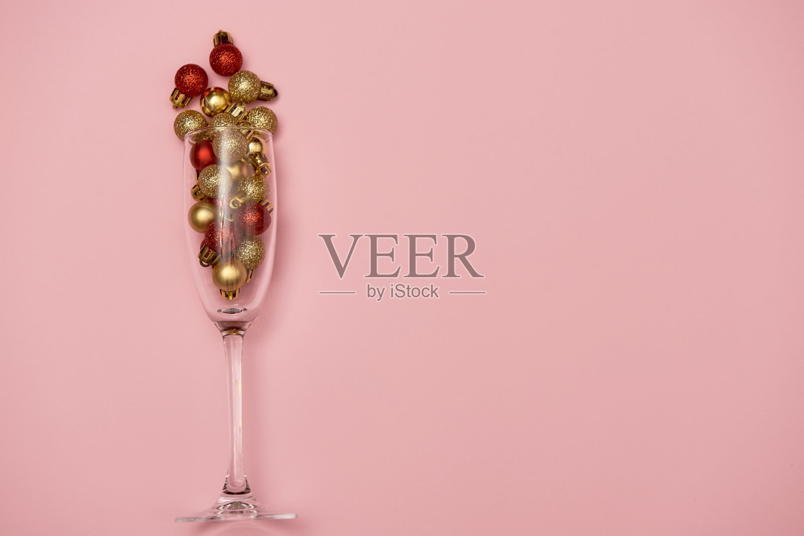 香槟酒杯与金色和红色的小玩意在淡粉色的背景，复制空间。最小，新年概念。俯视图，平躺照片摄影图片