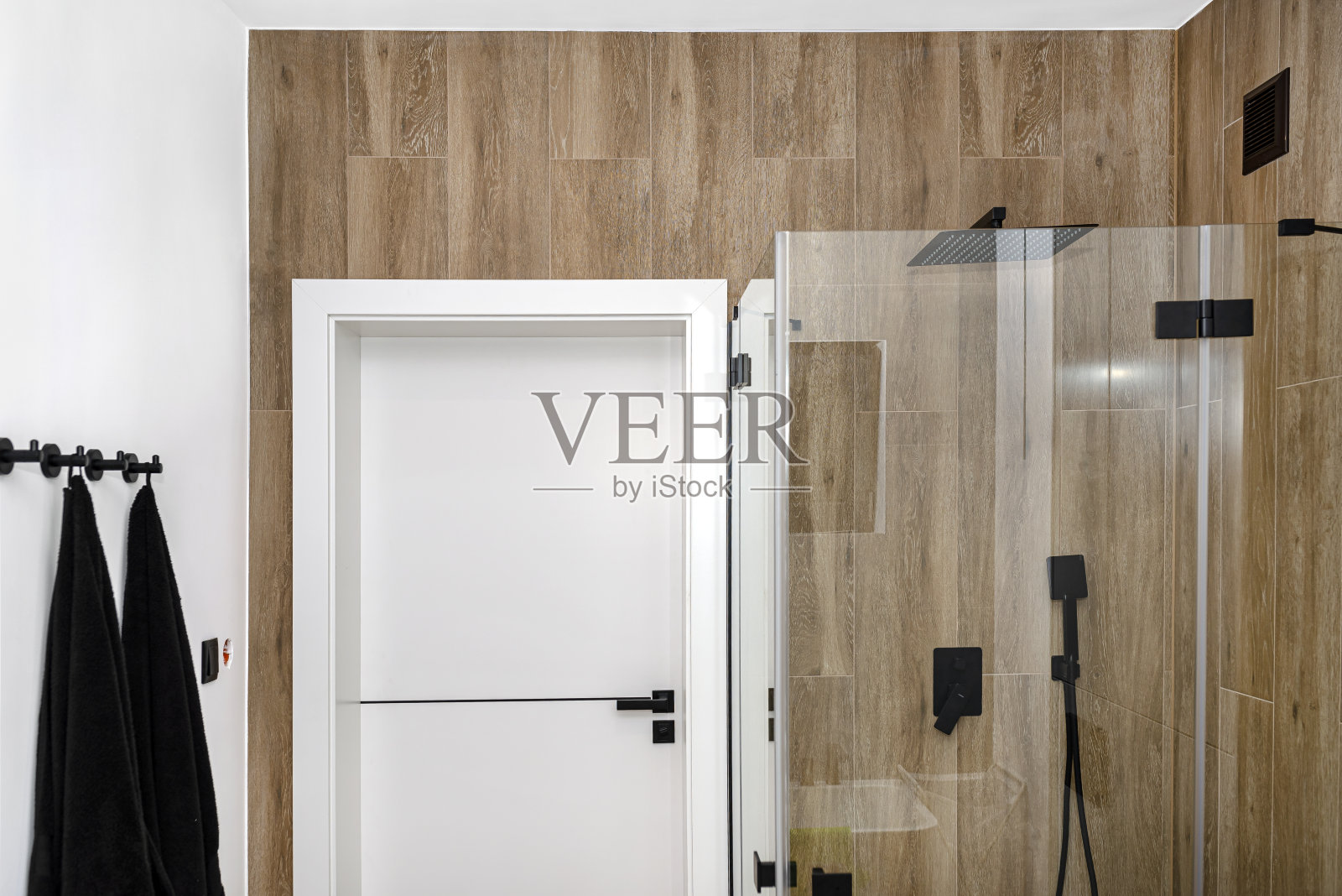 一间现代化的浴室，有一扇紧闭的淋浴门，铺着仿木瓷砖。照片摄影图片