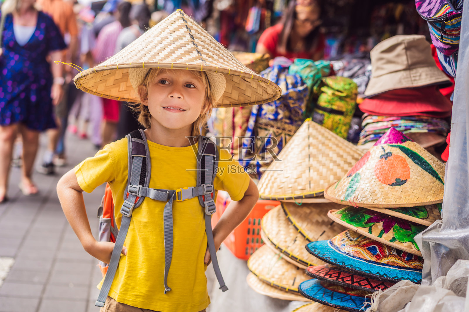 一个男孩在巴厘岛乌布的市场。在印尼著名的乌布市场，典型的纪念品商店出售巴厘岛的纪念品和手工艺品。巴厘岛的市场。当地居民的木制品和工艺品纪念品照片摄影图片