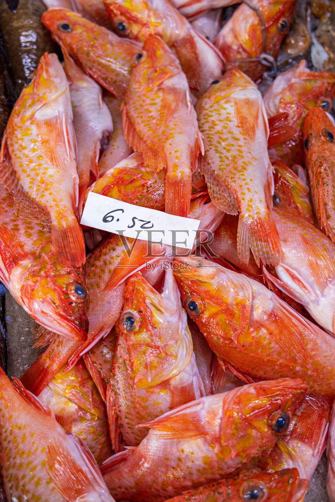 鱼贩子摊位上的盒子里装着红色的鱼照片摄影图片