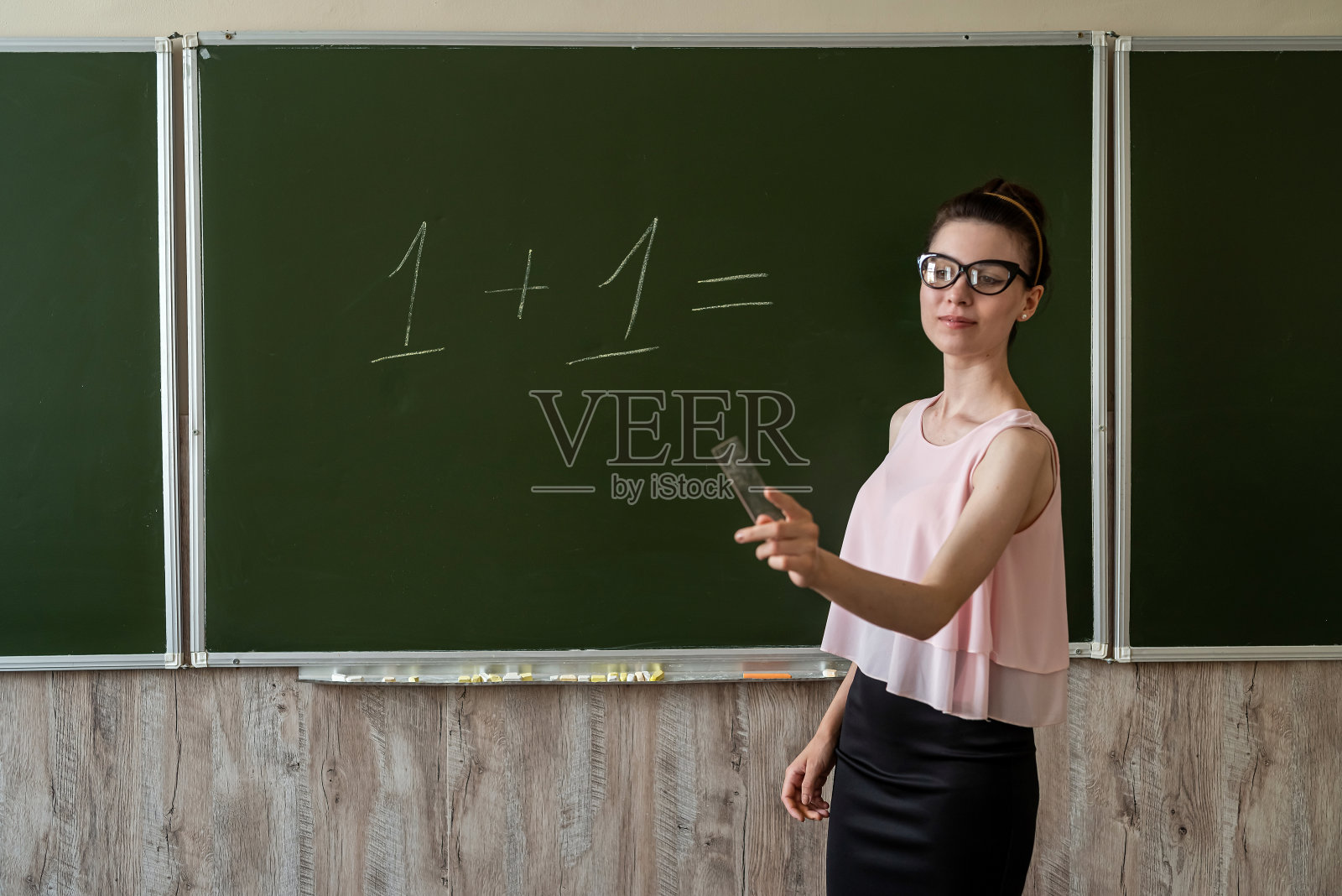 小学老师在黑板上写了一加一照片摄影图片