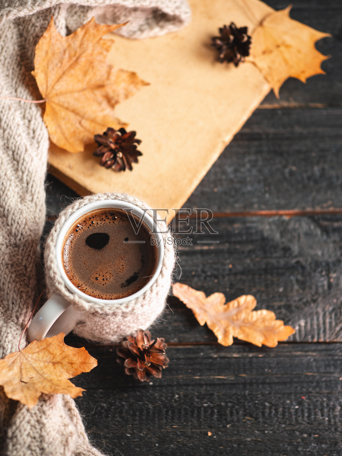 俯视图一杯浓咖啡放在一张黑色木桌上，针织暖和的秋冬衣服，一本旧书，干树叶照片摄影图片