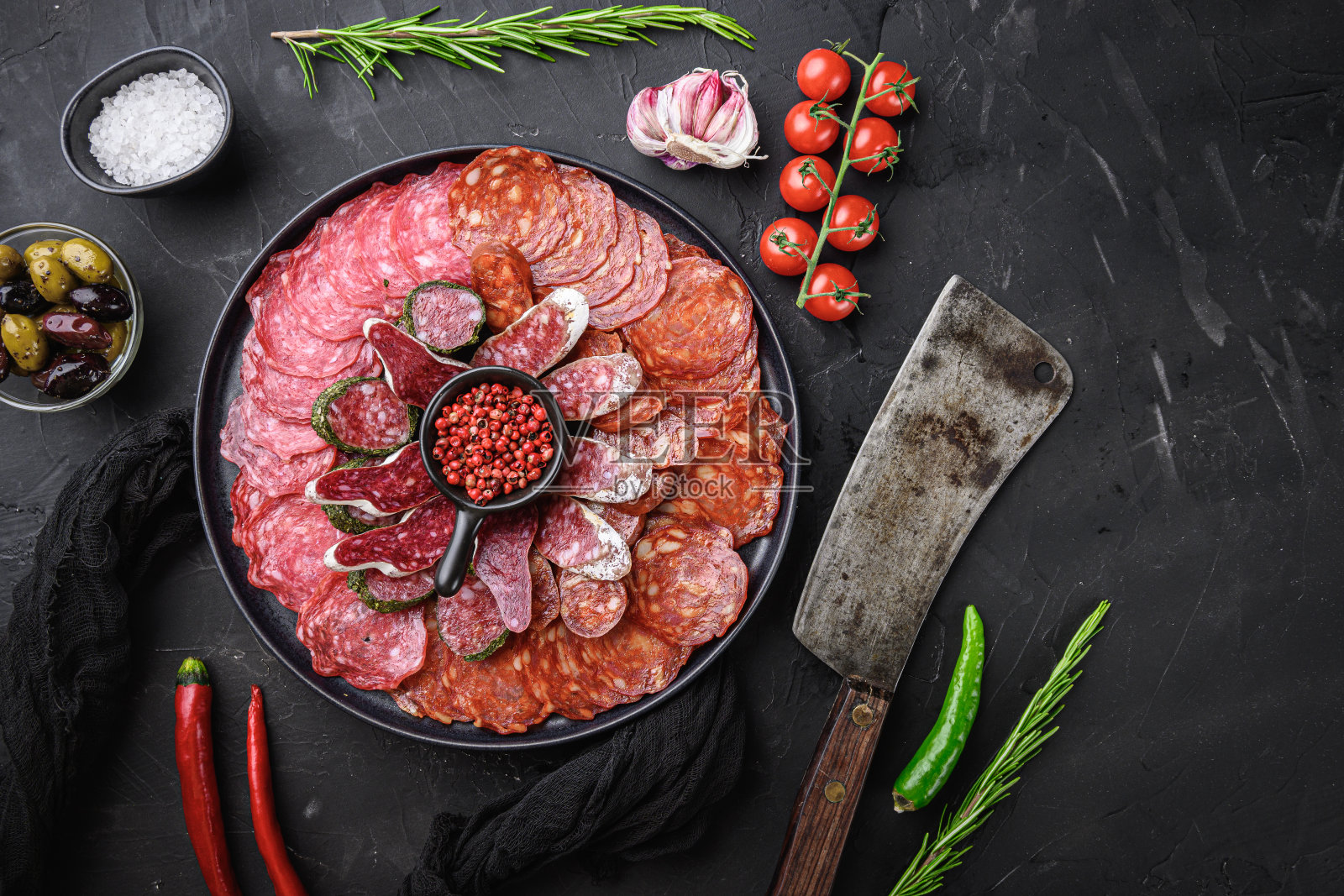 干腌香肠切成片，西班牙辣香肠，意大利腊肠在黑色背景上，平躺照片摄影图片