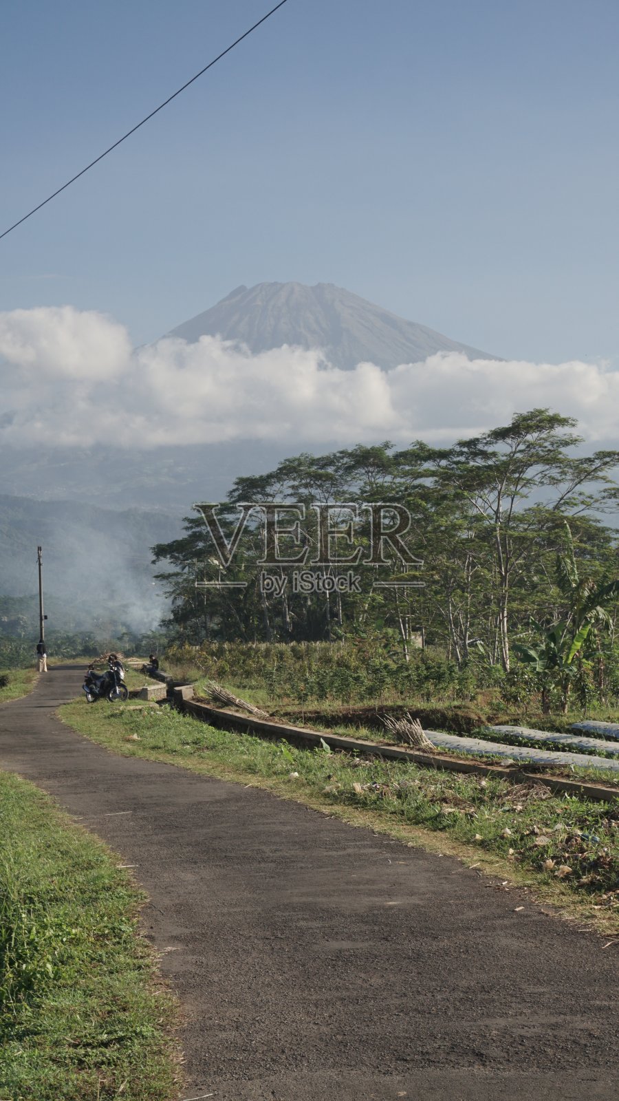 印度尼西亚农村的稻田，农民和鸭子在多云的山脉背景下。照片摄影图片