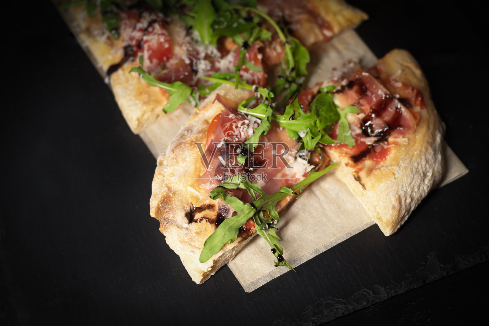 意大利熏火腿披萨，切成块，放在木板上。传统的意大利熏火腿披萨。照片摄影图片