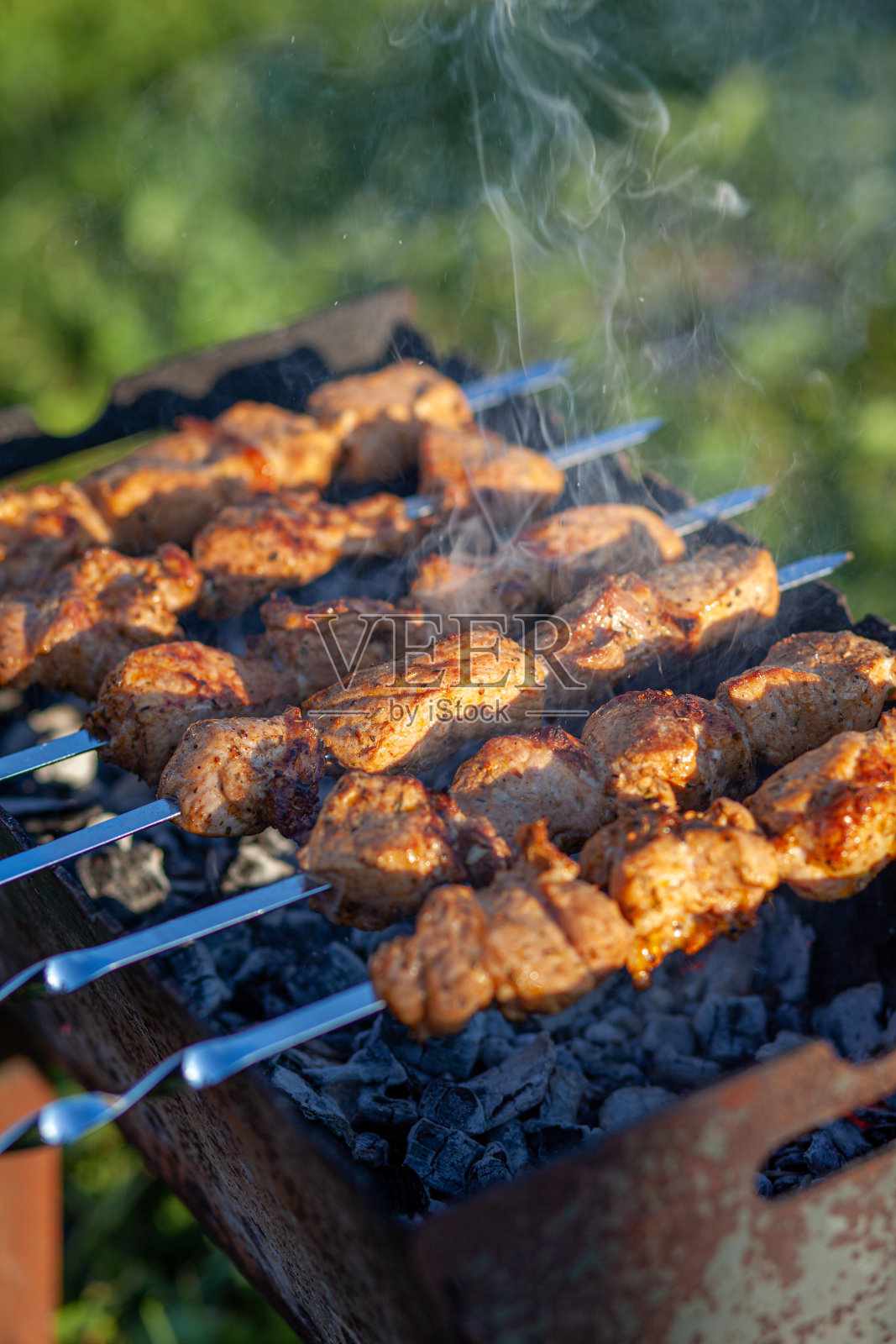 日落时分，烤肉架上用金属串成的肉片照片摄影图片