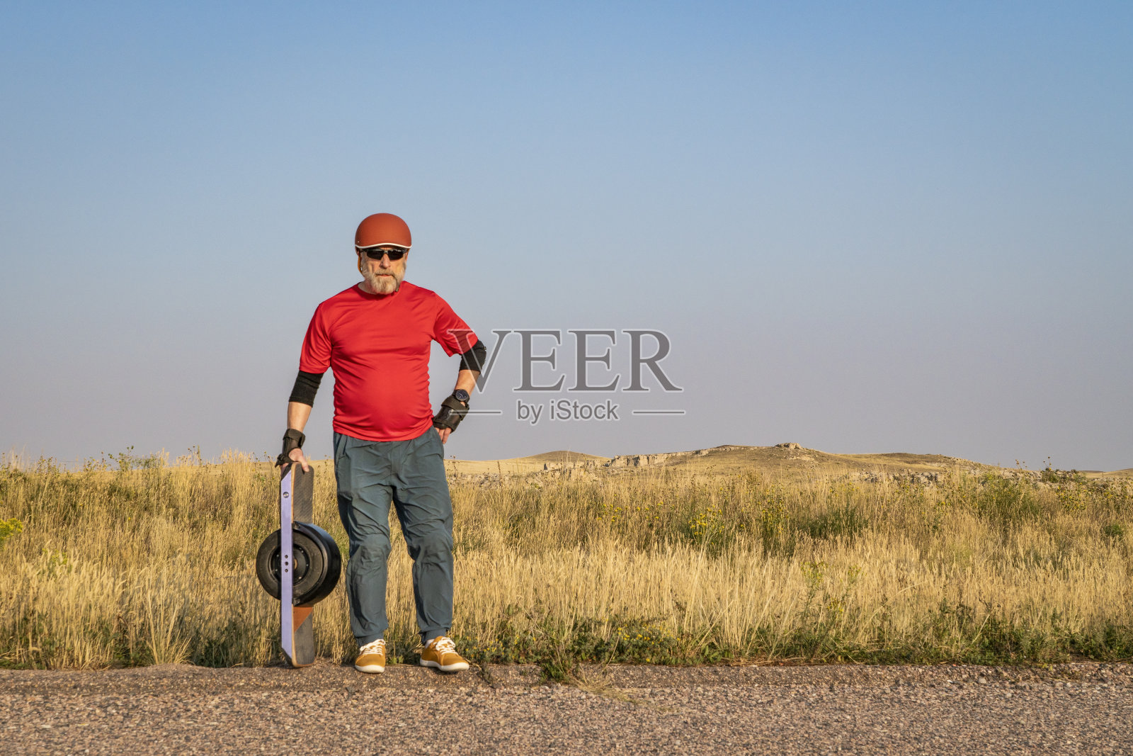 成熟的老年男子正在骑着单轮电动滑板照片摄影图片