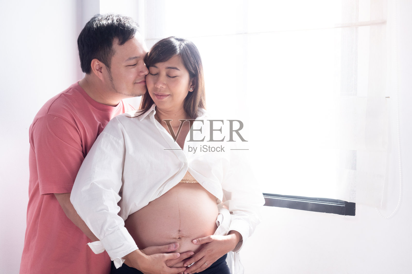 丈夫亲吻等待孩子的妻子，幸福的家庭爱和关怀。照片摄影图片