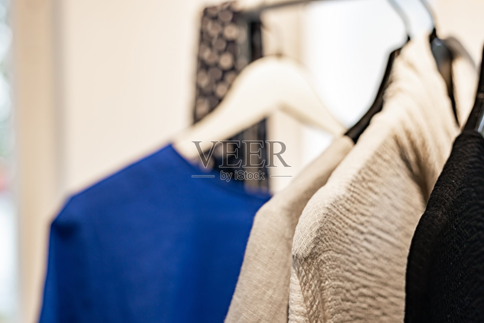 时尚时尚的女装挂在衣架上。展示室内品牌服装的特写镜头。光背景。时尚零售，展示厅，购物或季节性销售概念。有选择性的重点照片摄影图片