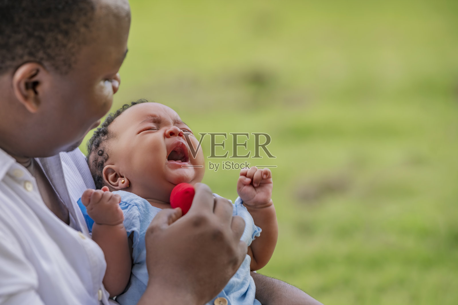 女婴在哭，她的父亲试图安慰她。照片摄影图片