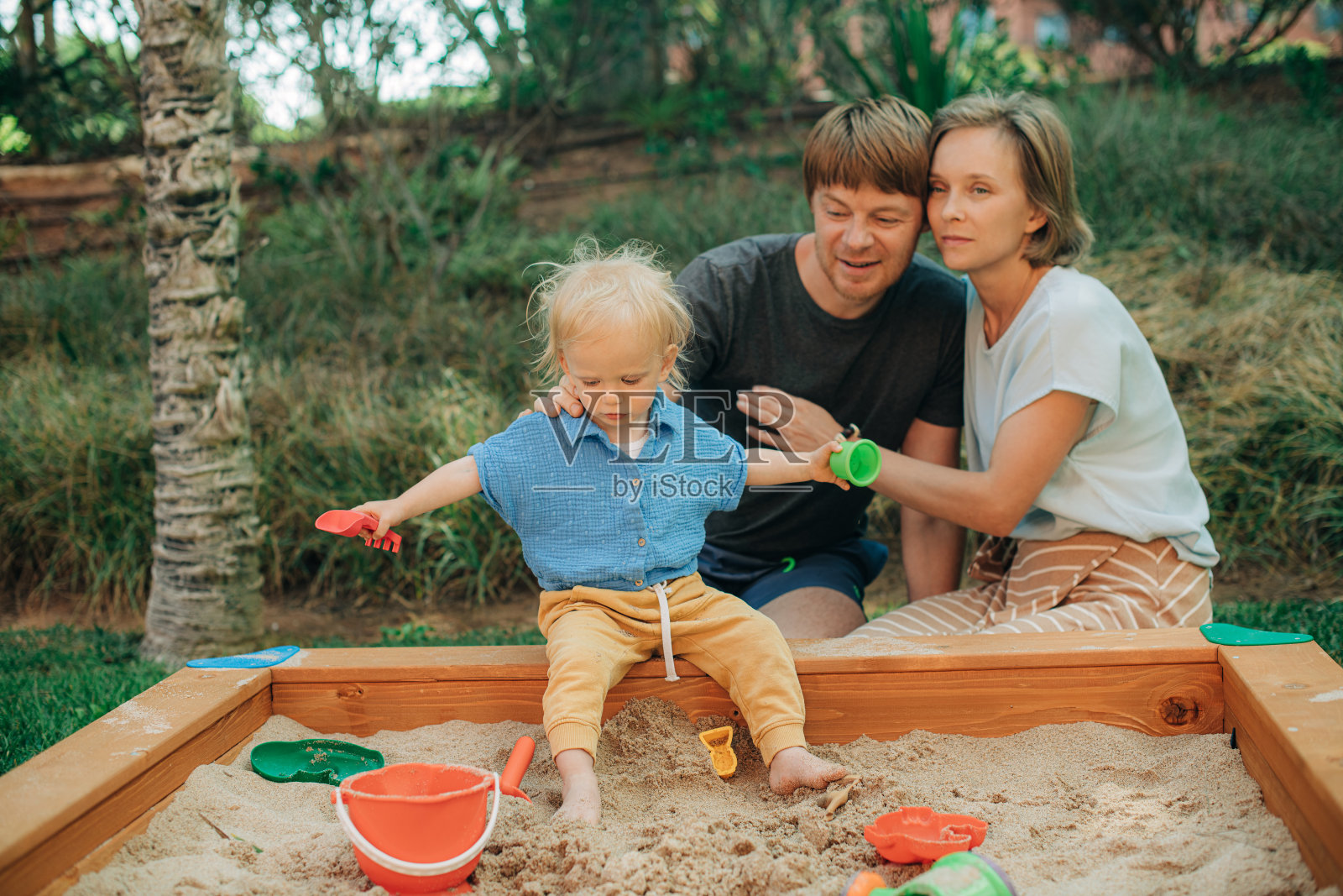 在沙坑里照顾小孩的幸福夫妇照片摄影图片