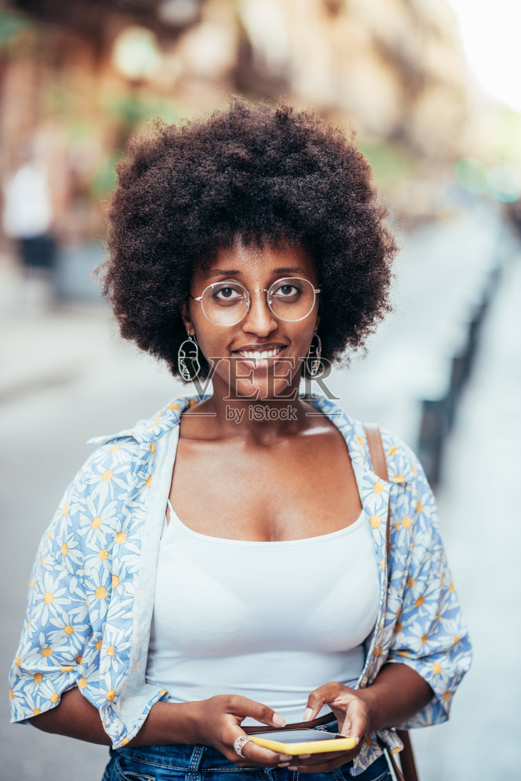 一名非洲妇女拿着手机看相机的竖像照片摄影图片