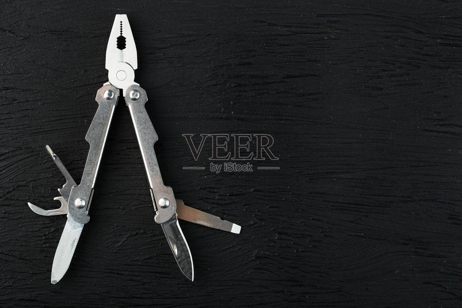 Multitool是一个在黑色背景上的多功能工具。具有自由空间的扩展多工具的概念。照片摄影图片