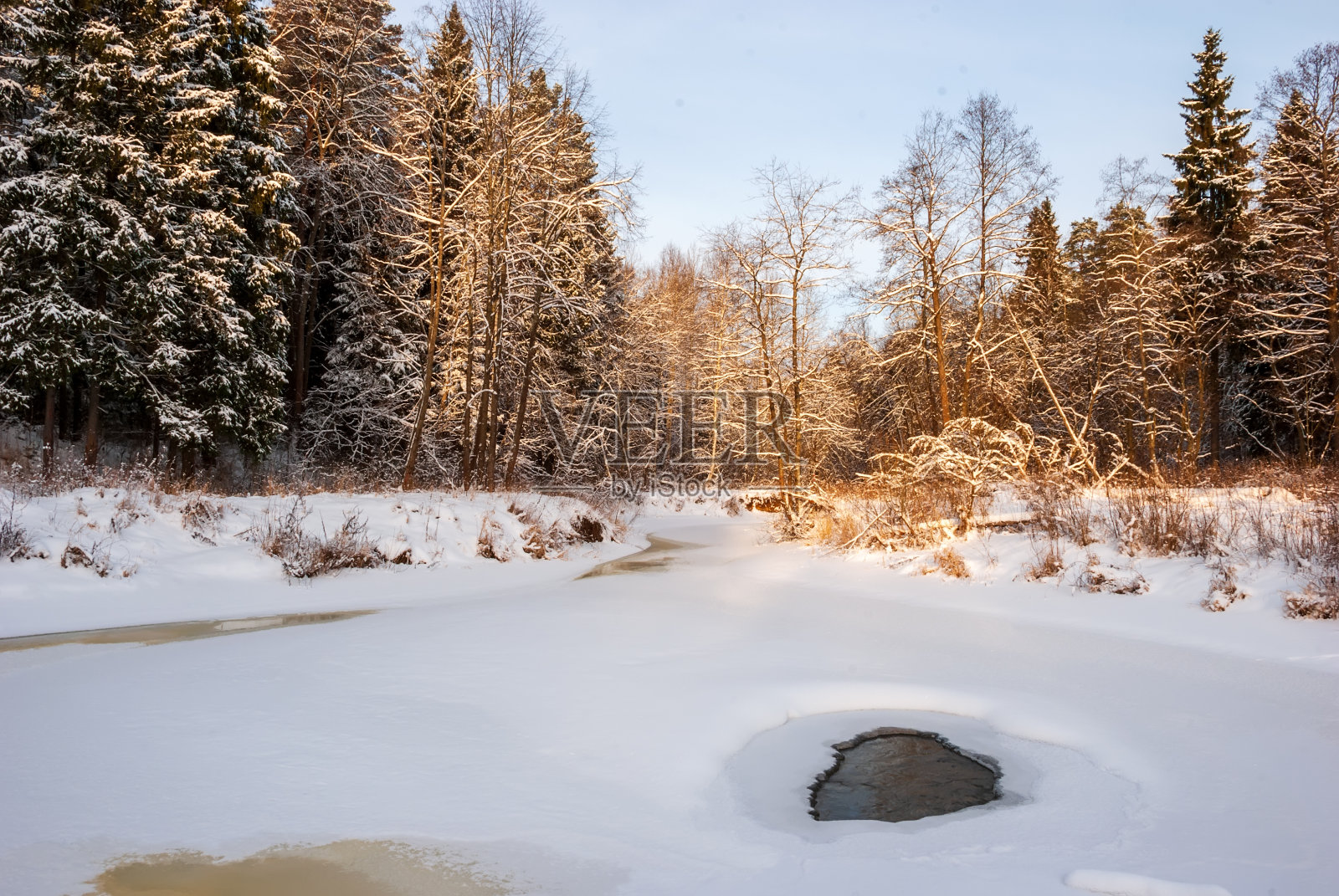 日落时的冬季风景。河床、云杉和桦树是真正的俄罗斯景观。照片摄影图片