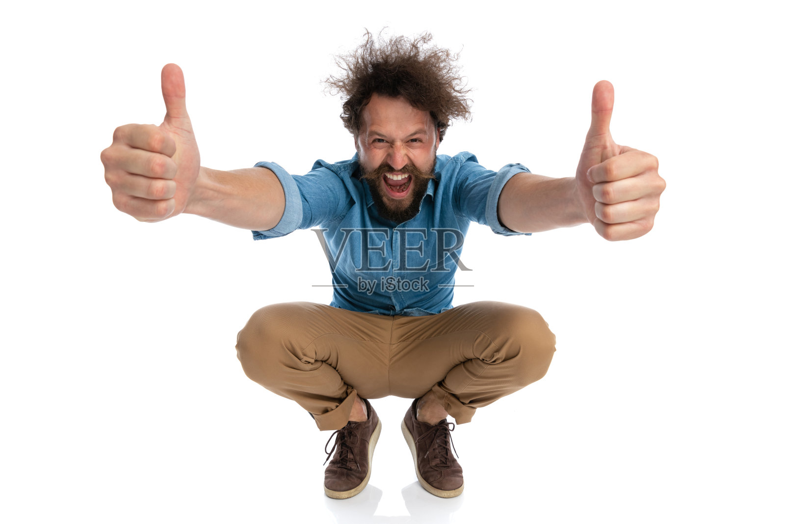 有魅力的休闲男人蹲着，竖起大拇指照片摄影图片