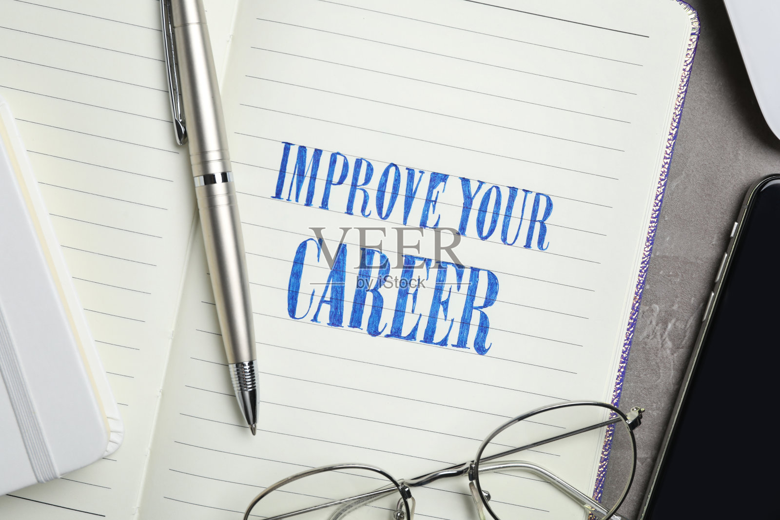 写着“改善你的事业”的笔记本，桌上的钢笔和眼镜，特写镜头照片摄影图片