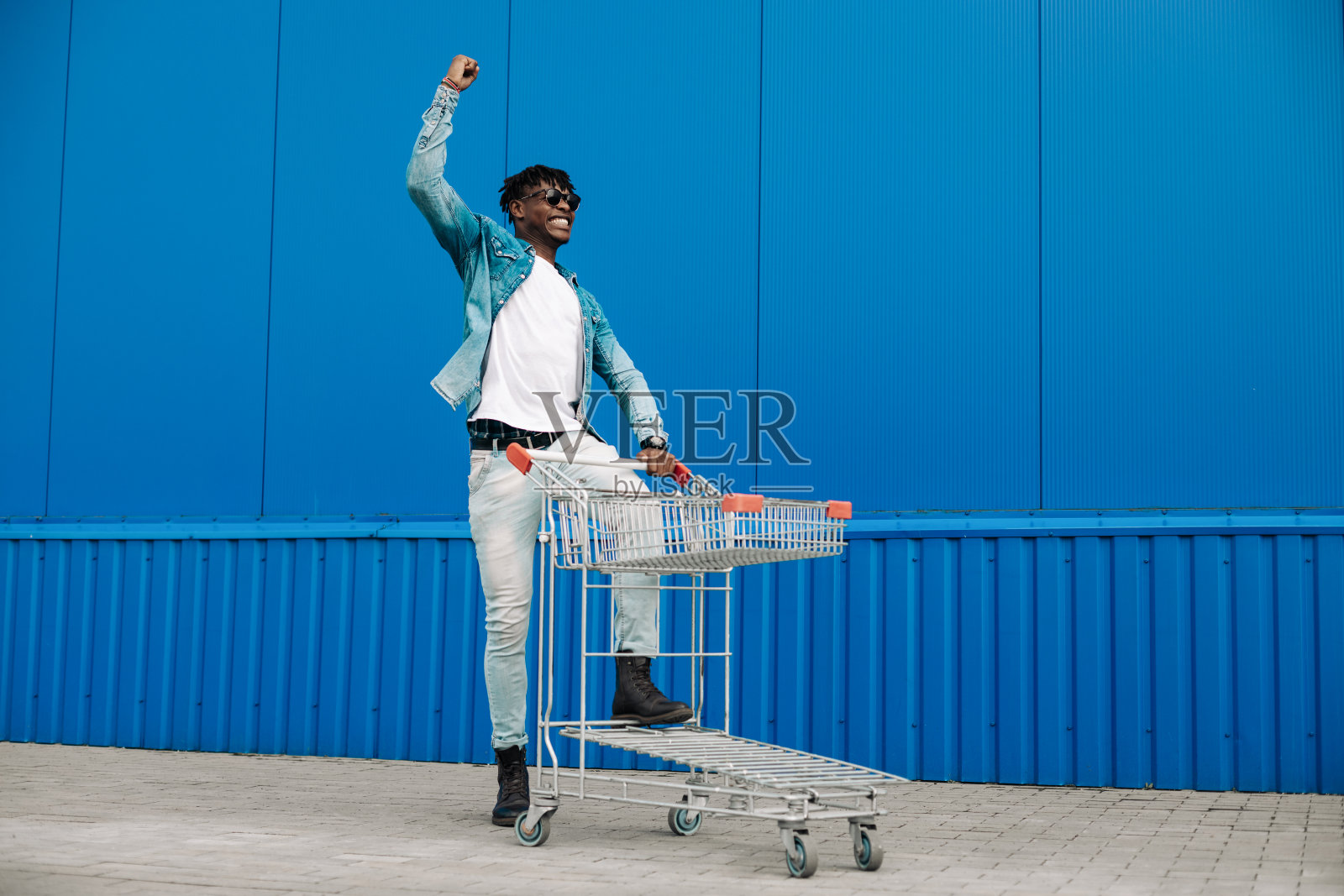 非洲购物推车，男人正在购物商场附近，高兴地举起双手照片摄影图片