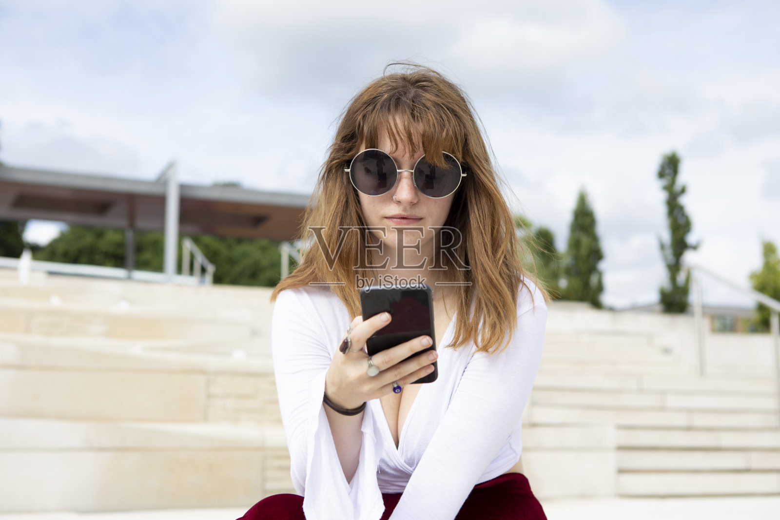 夏天，年轻女子坐在石阶上使用手机照片摄影图片