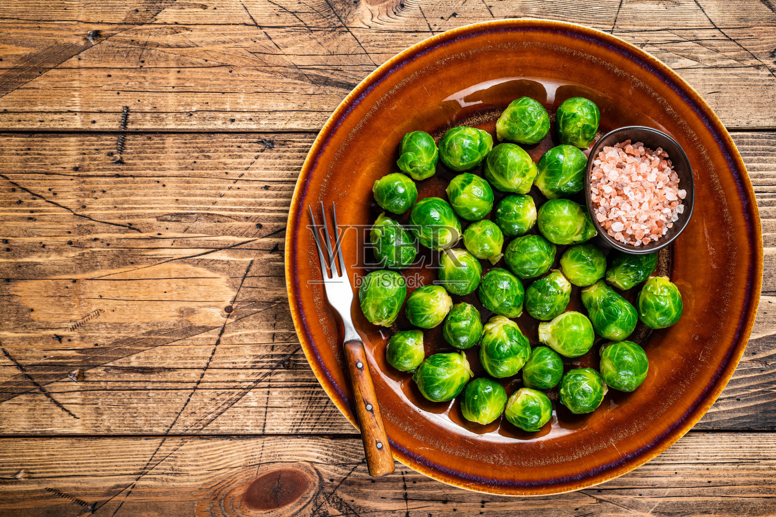 生的球芽甘蓝在一个质朴的盘子里，加盐。木制背景。前视图。本空间照片摄影图片