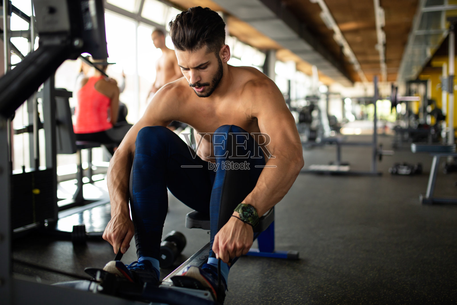 年轻健康的男人在健身房锻炼以保持健康。运动人健身概念照片摄影图片