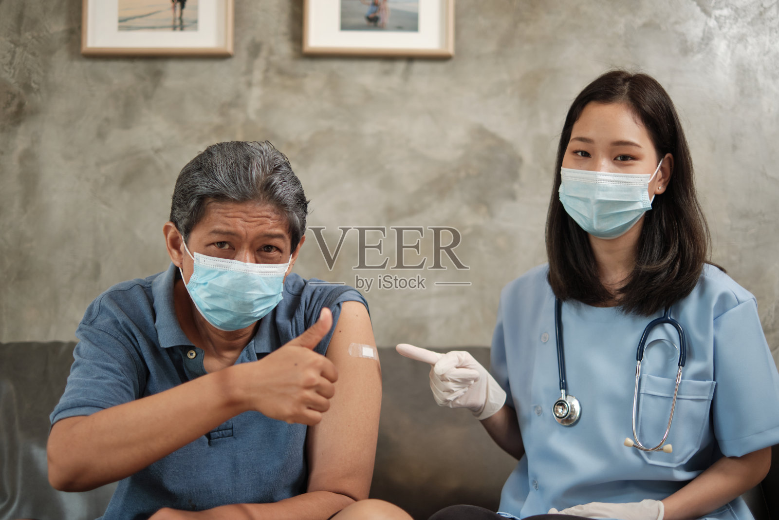 戴口罩的长者在接种疫苗时竖起大拇指。照片摄影图片