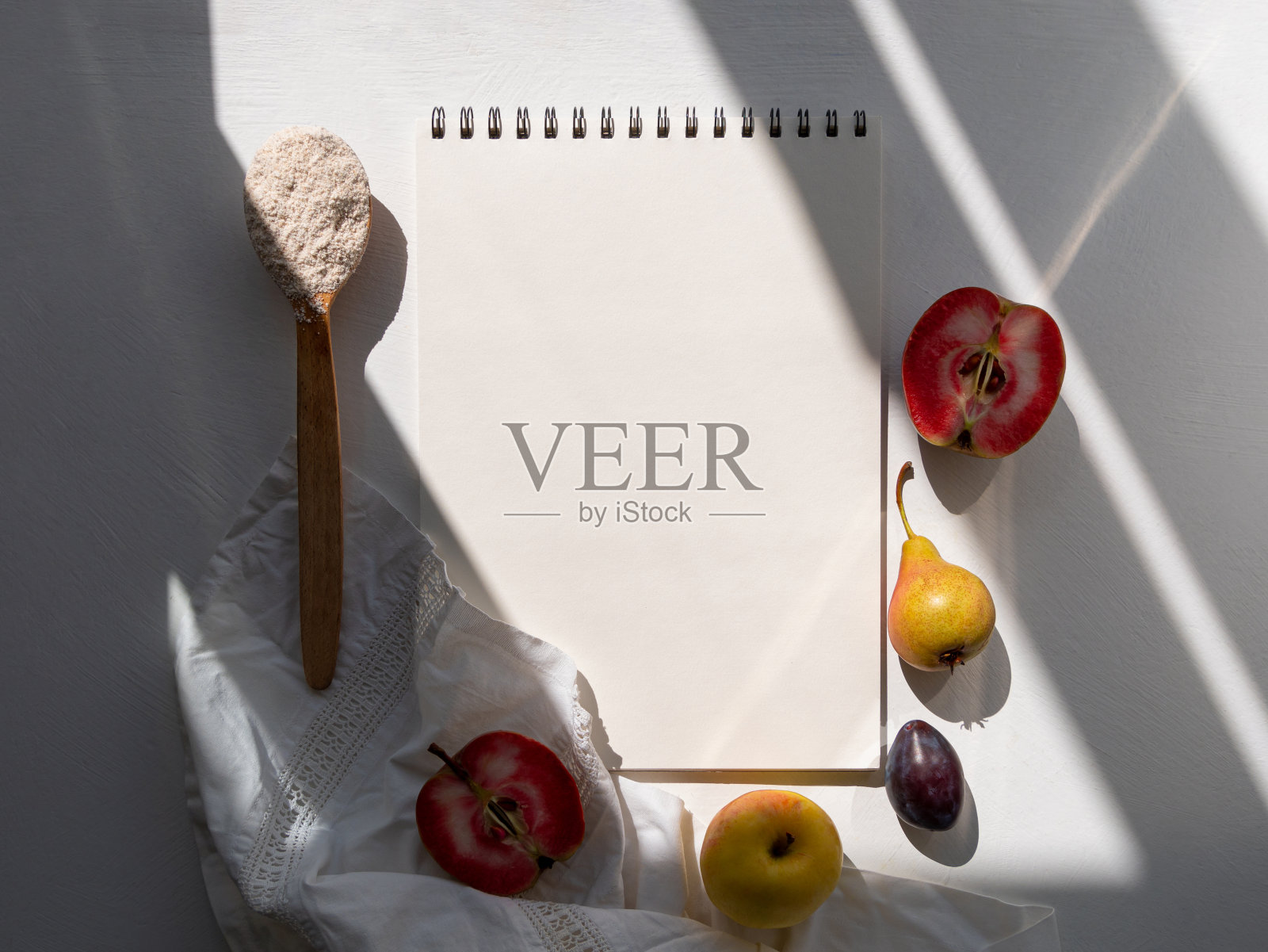 秋天平铺开的食谱，红苹果梨李子亚麻布桌布，背景光刺眼的阴影。空白配方笔记本照片摄影图片