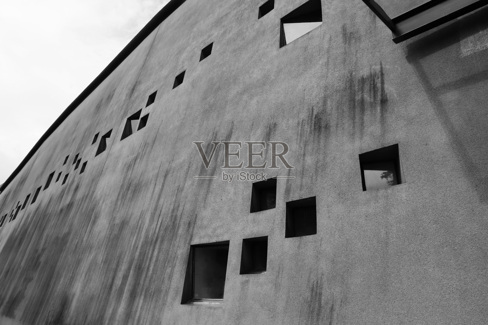有着方形窗户的古老建筑。灰色的乡村混凝土立面。黑色和白色。照片摄影图片