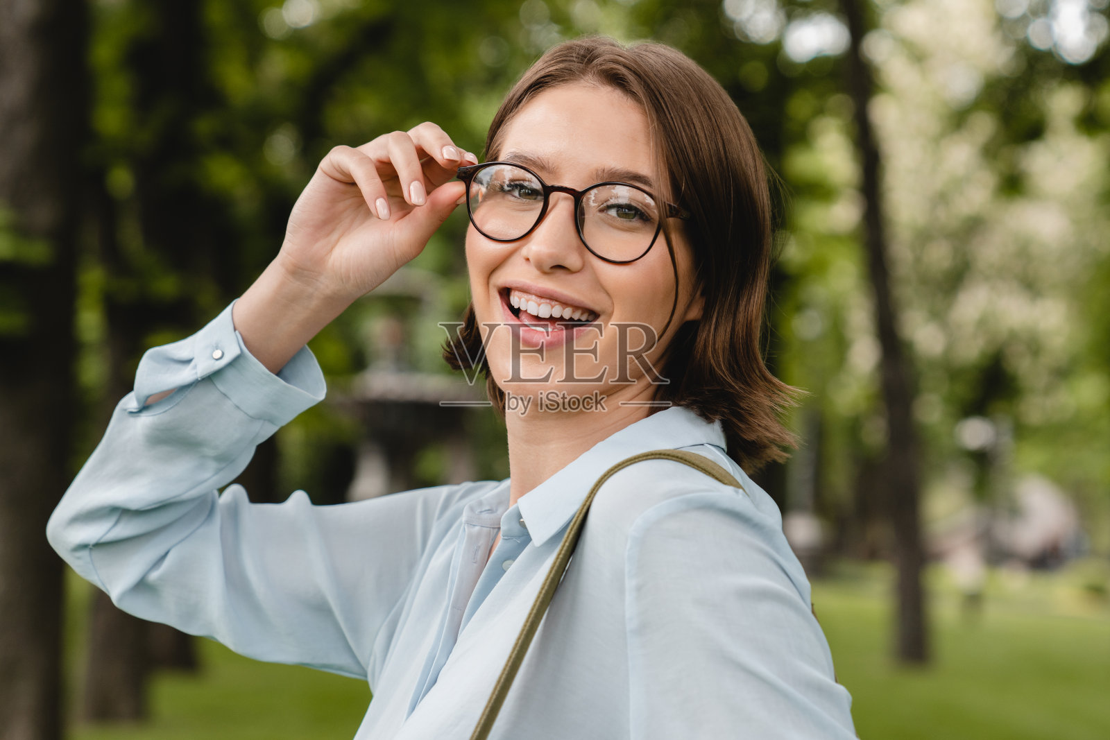年轻成功的商人，女学生，教师，自由职业者，家庭教师，戴着眼镜，穿着正式的服装，走在城市城镇公园看着摄像机。近距离射杀。照片摄影图片