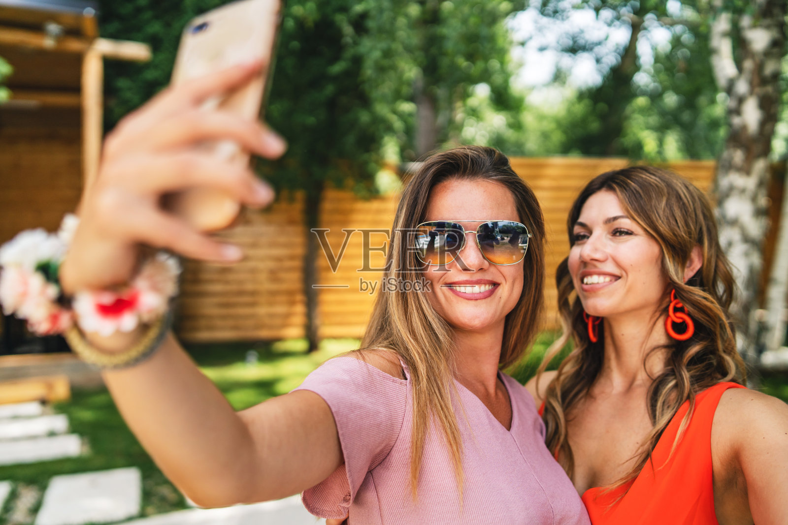 两个女性女性朋友或姐妹在阳光明媚的夏日里用手机自拍快乐微笑的照片照片摄影图片