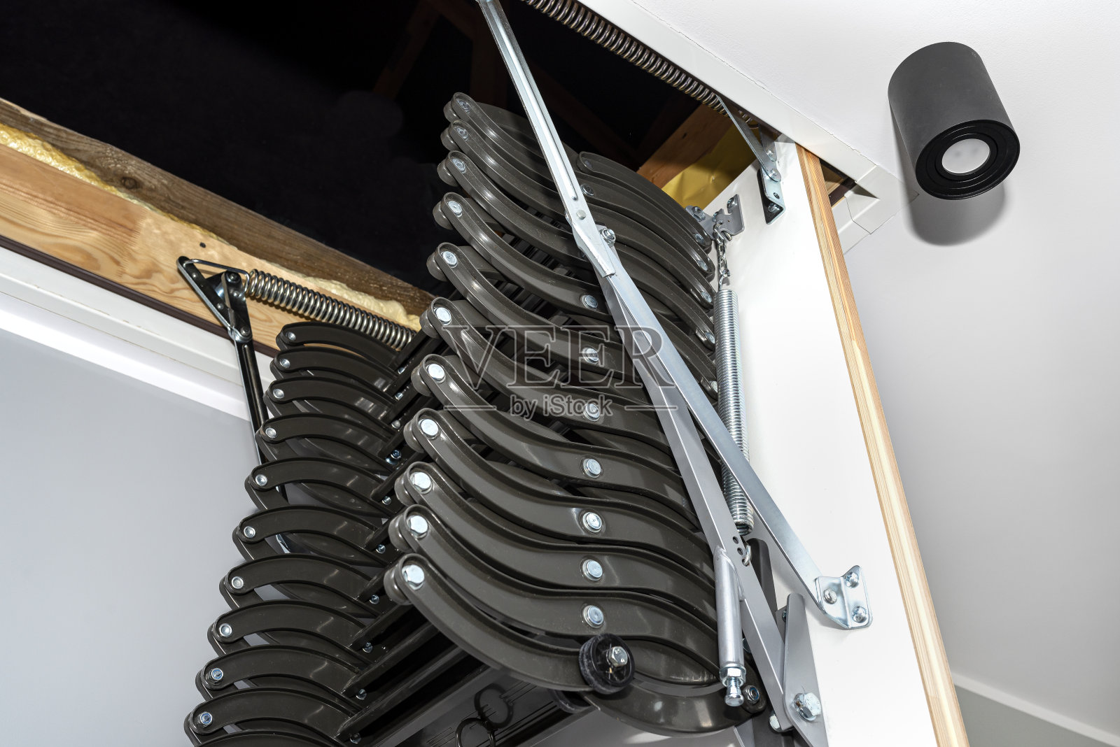 可折叠的金属楼梯通向阁楼的天花板，开放式的舱口和复杂的楼梯，现代感十足。照片摄影图片