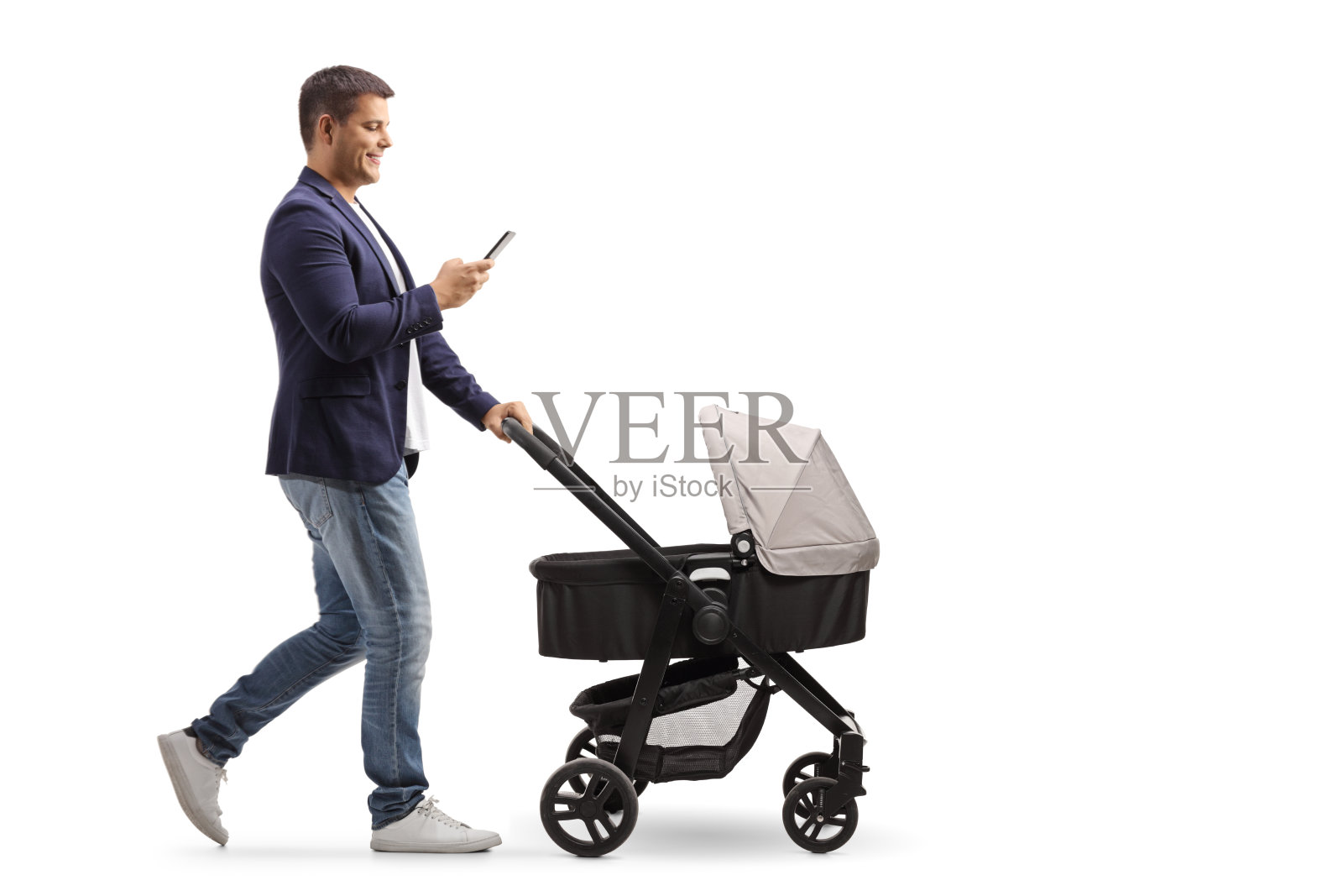 一张父亲推着婴儿车边走边打手机的全长侧面照片照片摄影图片