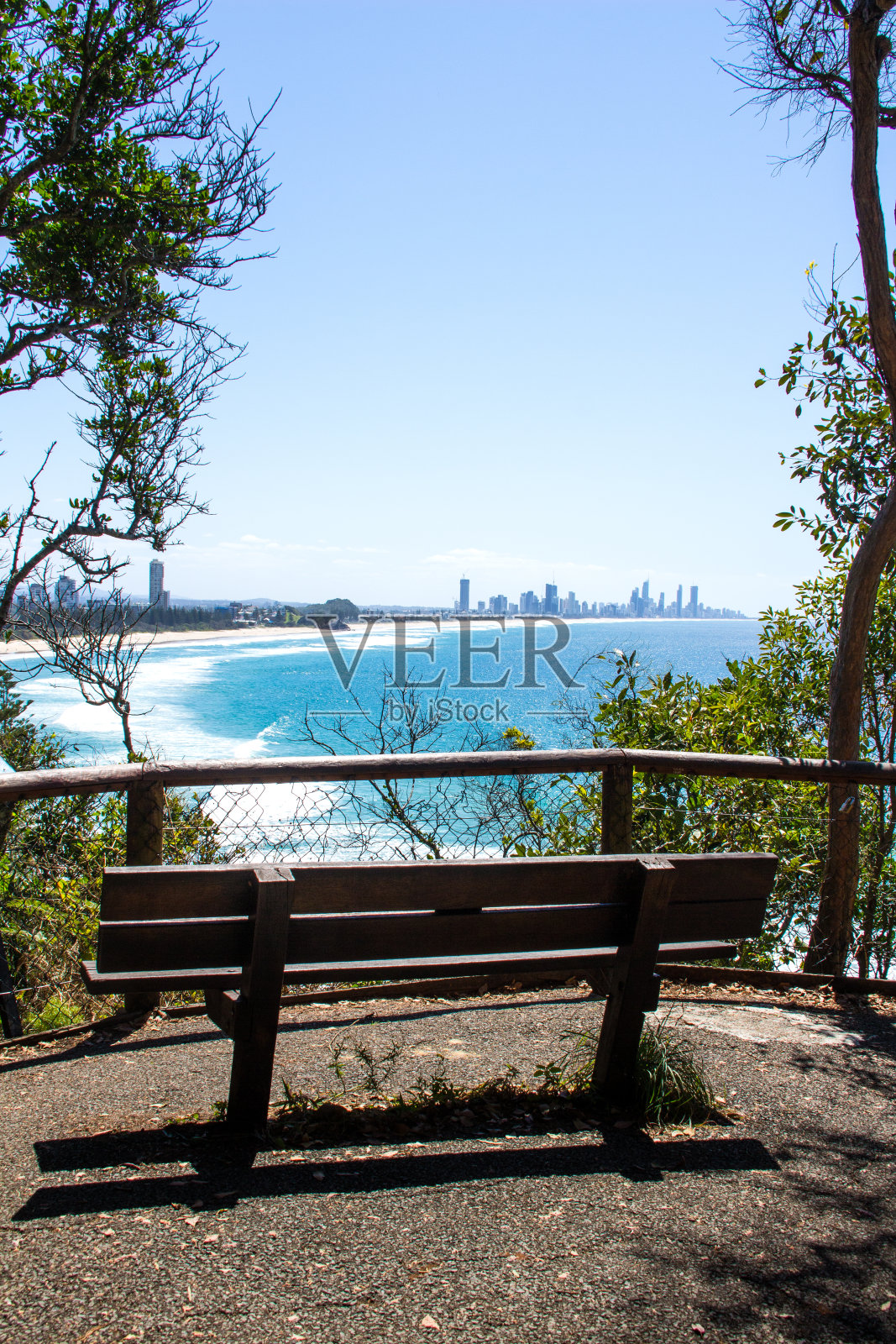 从伯利岬向外眺望，来到伯利岬和冲浪者天堂。木材长凳座位在前景。后面是蓝色的海洋。Burleigh Heads澳大利亚昆士兰照片摄影图片