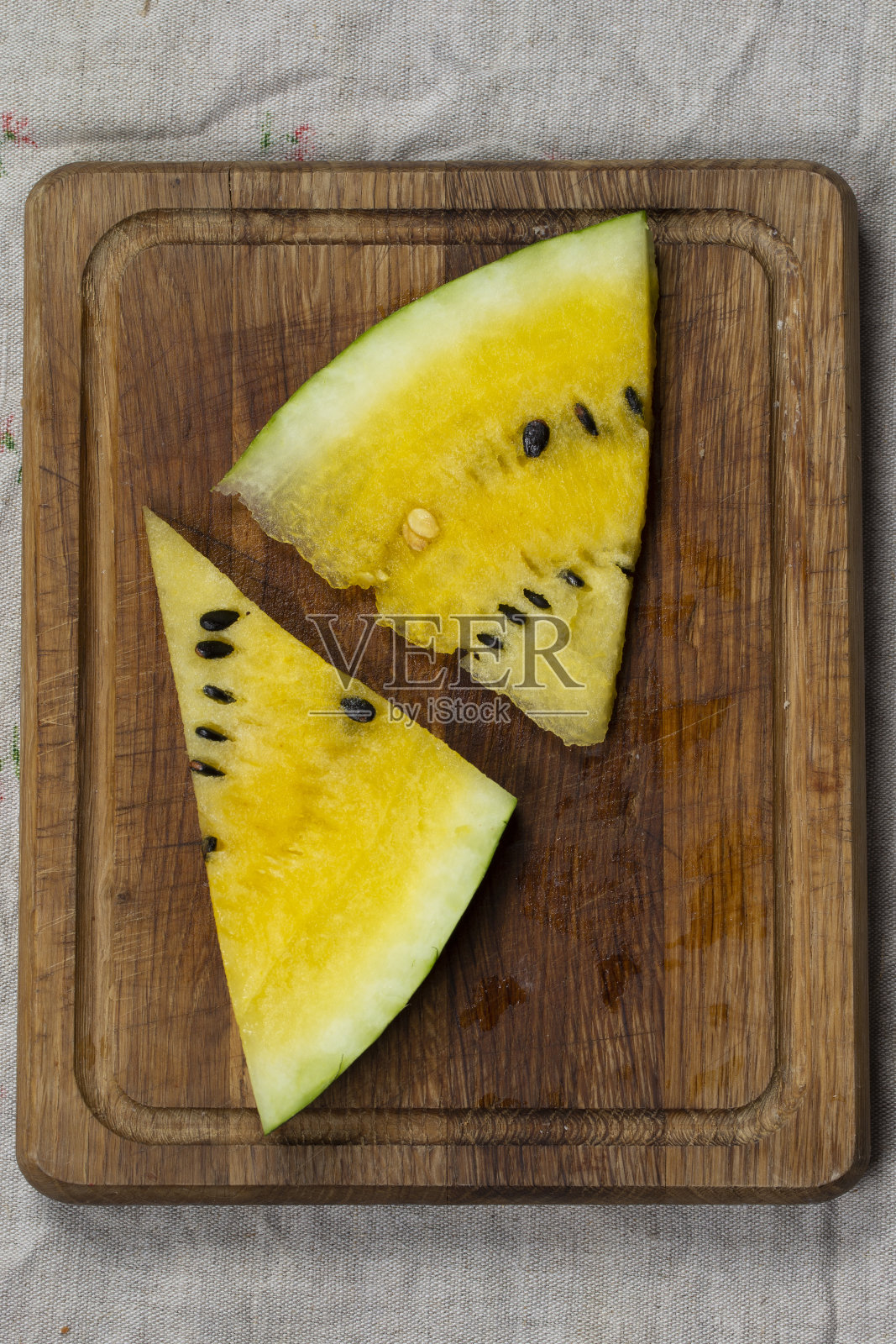 木制背景上的黄色西瓜片。照片摄影图片