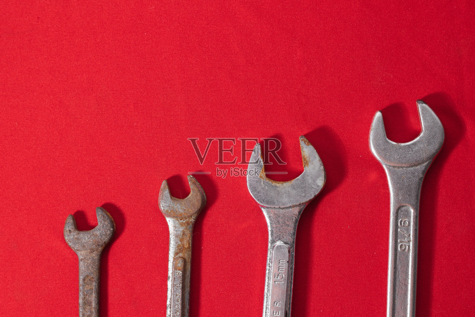扳手，锈迹斑斑，按升序排列在红色背景上，为广告文字留出空间。构造工具照片摄影图片