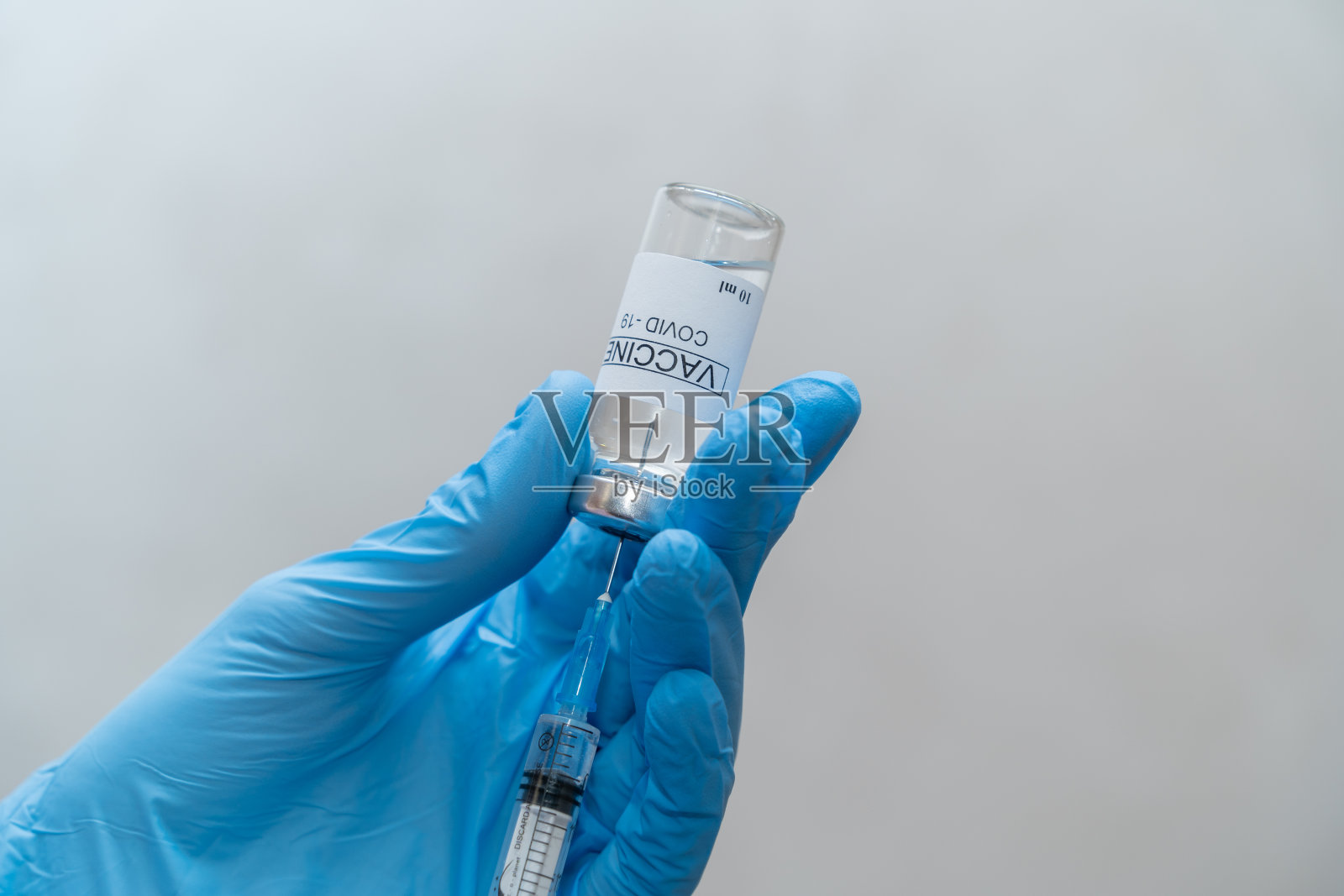 医生将冠状病毒疫苗注入注射器。照片摄影图片