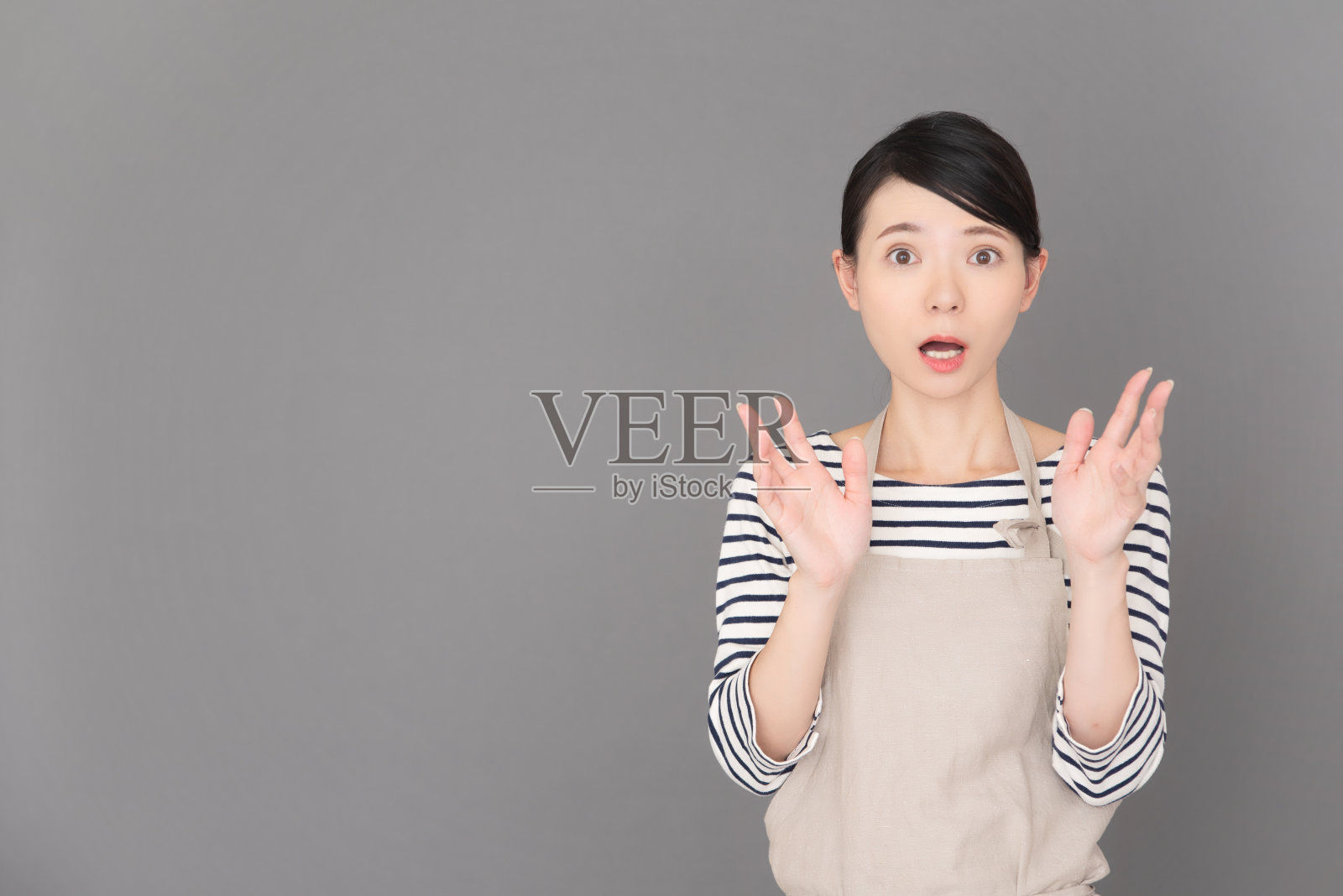 一个穿着围裙的女人站在灰色背景前照片摄影图片