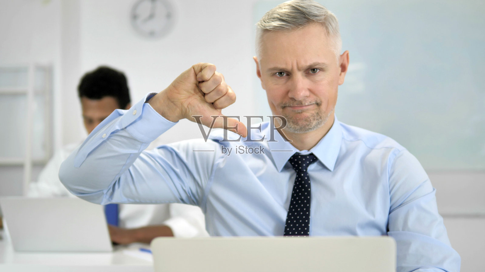 白发商人在办公室的大拇指向下照片摄影图片