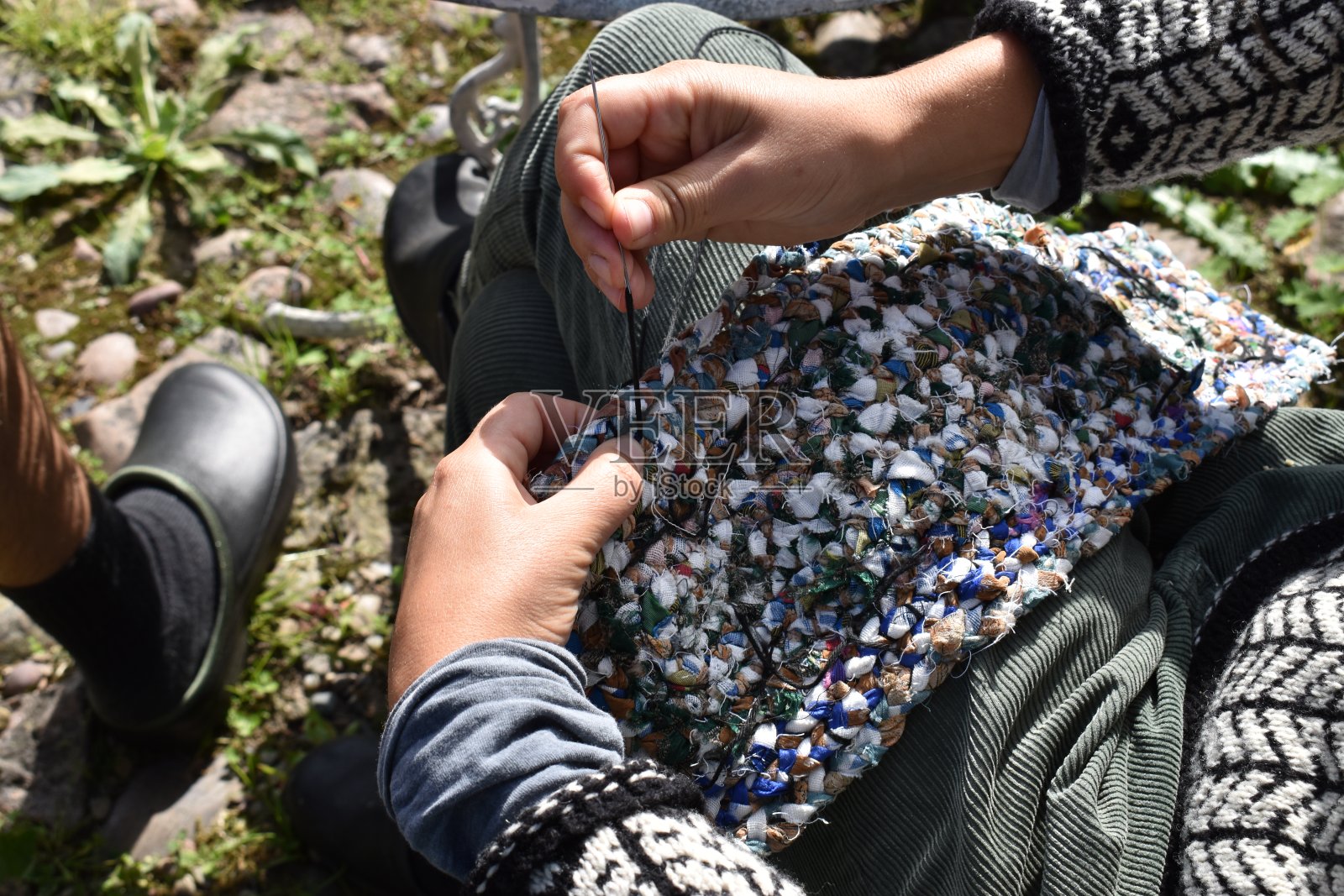 一位年轻女子在手工编织的地毯上撒播。照片摄影图片