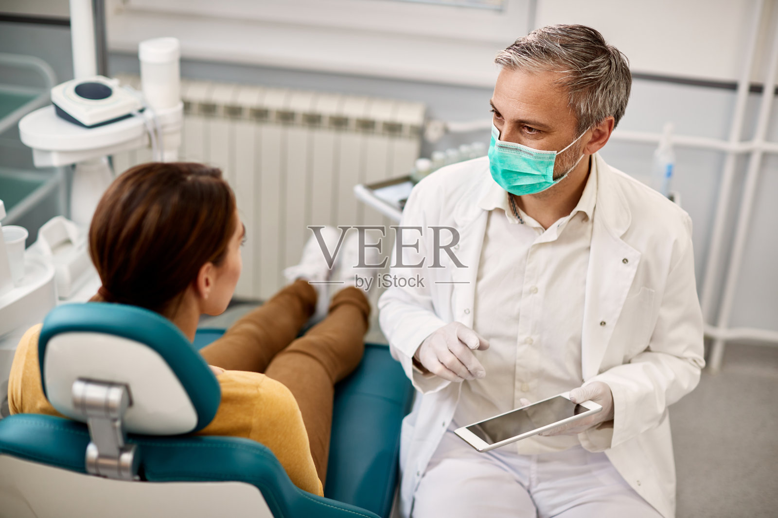 牙医在诊所使用触控板与病人预约。照片摄影图片