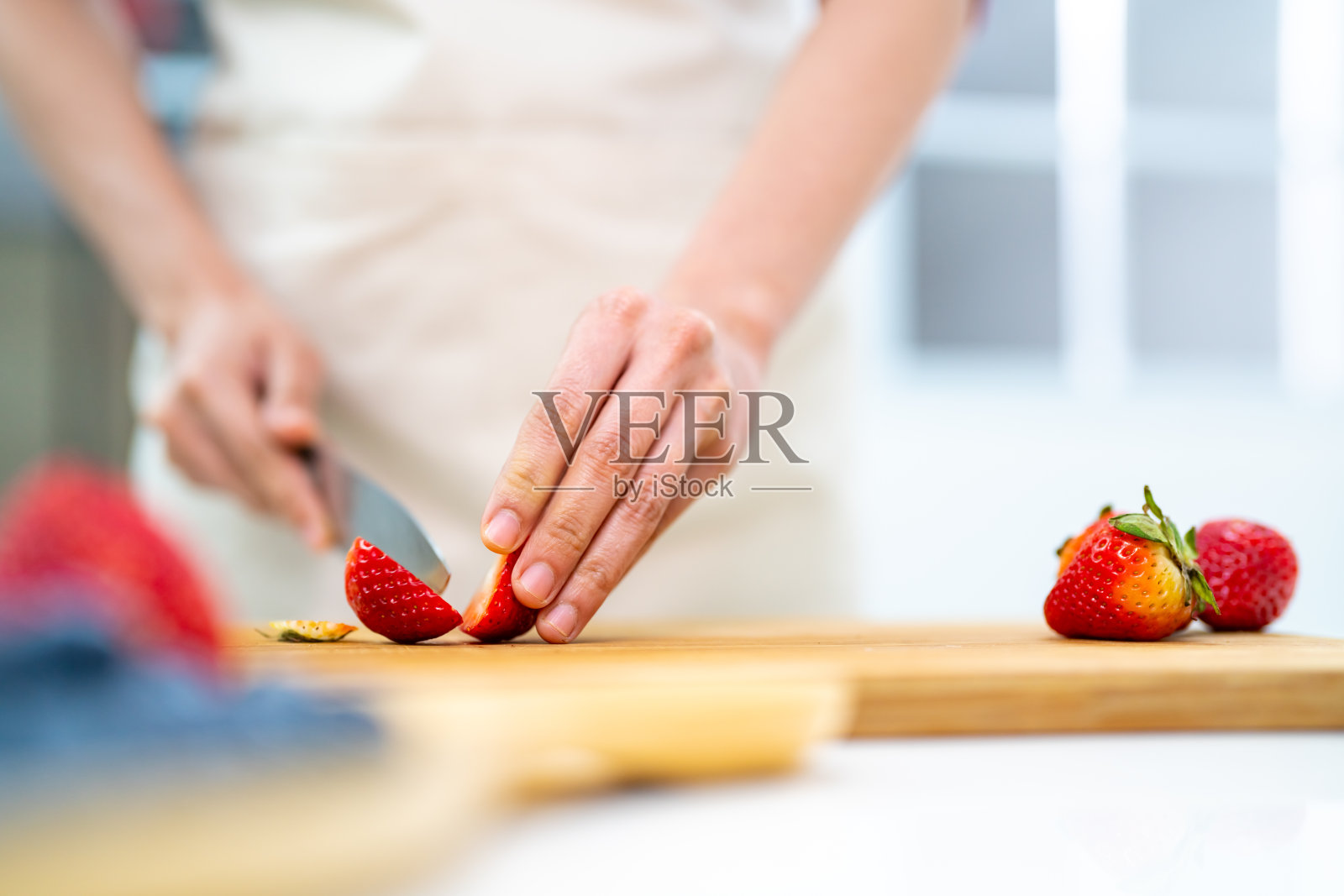 亚洲妇女在厨房切新鲜水果做水果挞。照片摄影图片