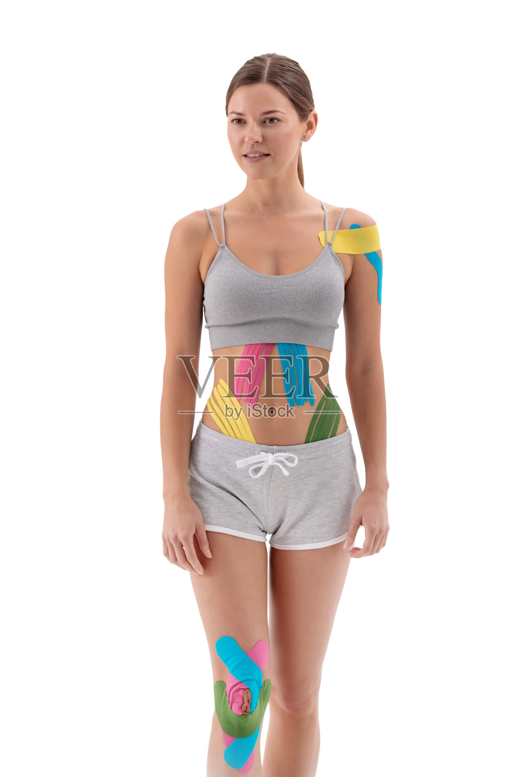 理疗胶带贴在一个被隔离在白色上的年轻女运动员身上。理疗，肌内贴，运动机能学和康复治疗概念。照片摄影图片