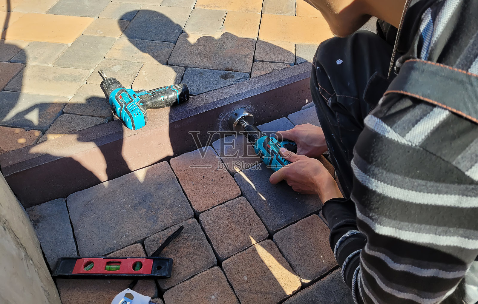 在混凝土路缘钻孔以安装灯具。照片摄影图片