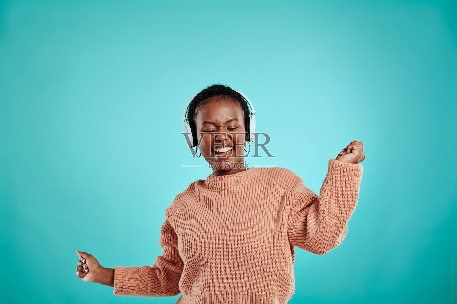 一名女子戴着耳机，站在蓝绿色背景下照片摄影图片