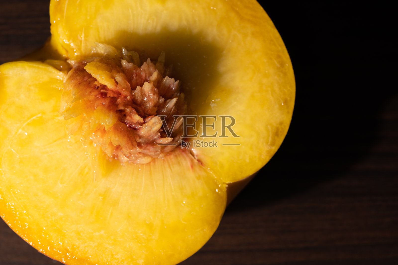 我把桃子切成两半，但果肉还附着在种子上照片摄影图片