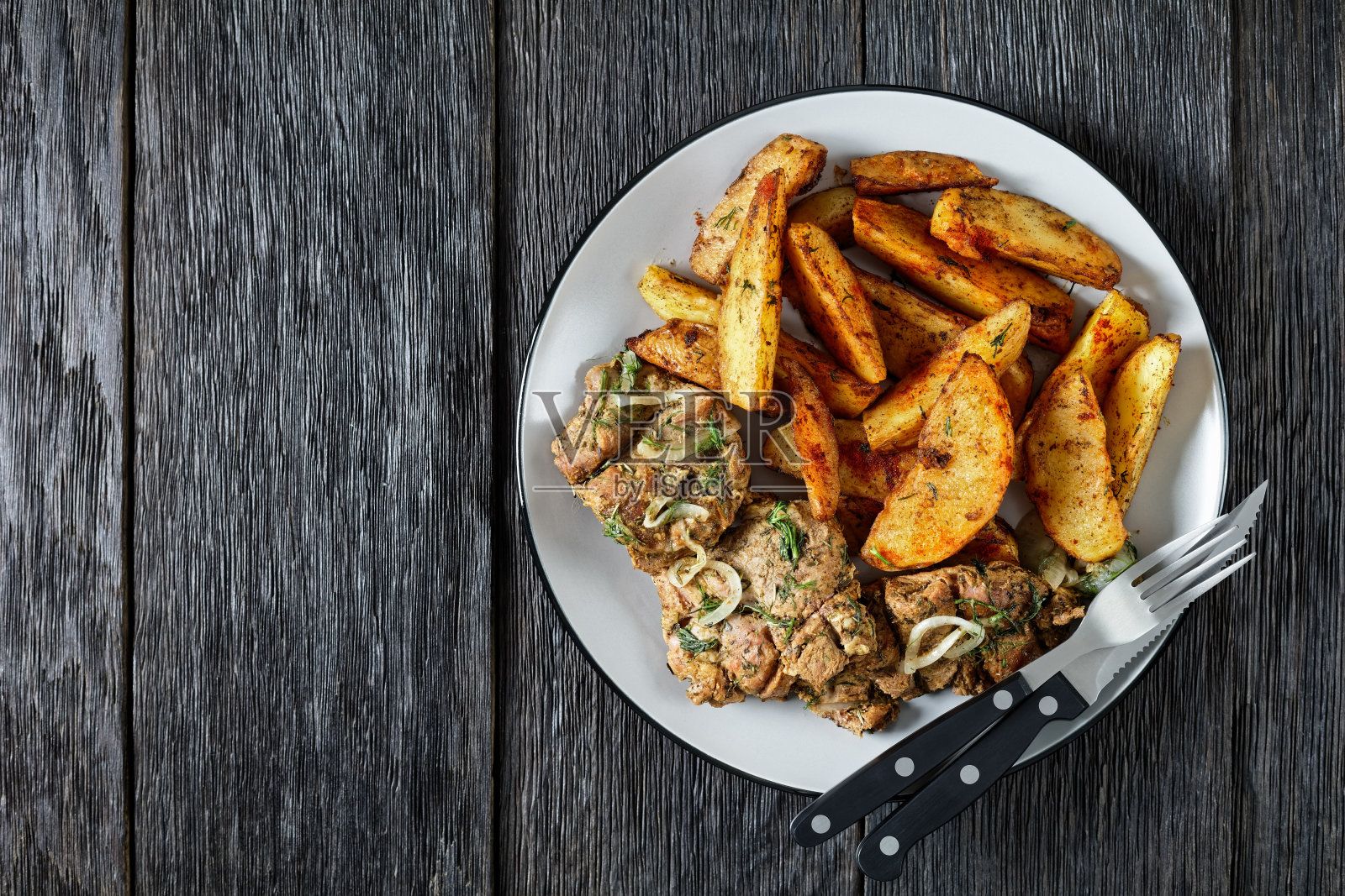 烤猪肩牛排配烤土豆，配辣椒和莳萝调味，放在一个质朴的木桌上，从上面水平观看，平躺，自由空间照片摄影图片