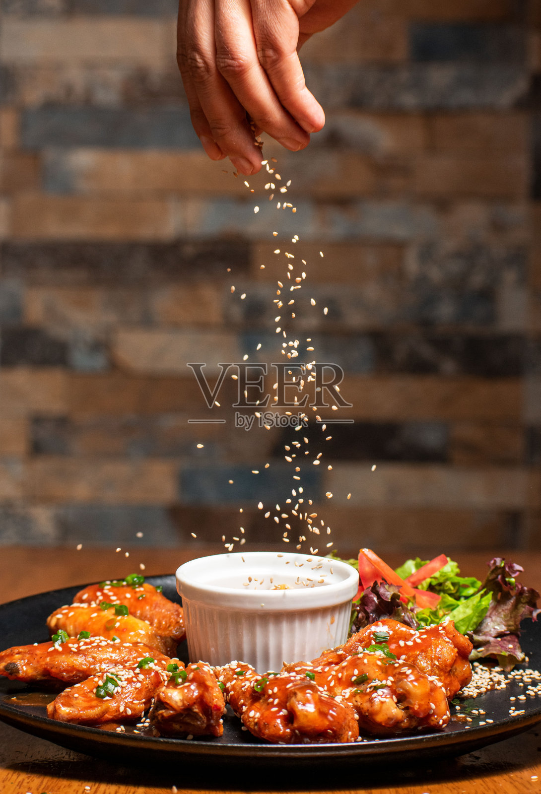 手往热鸡翅里撒芝麻照片摄影图片